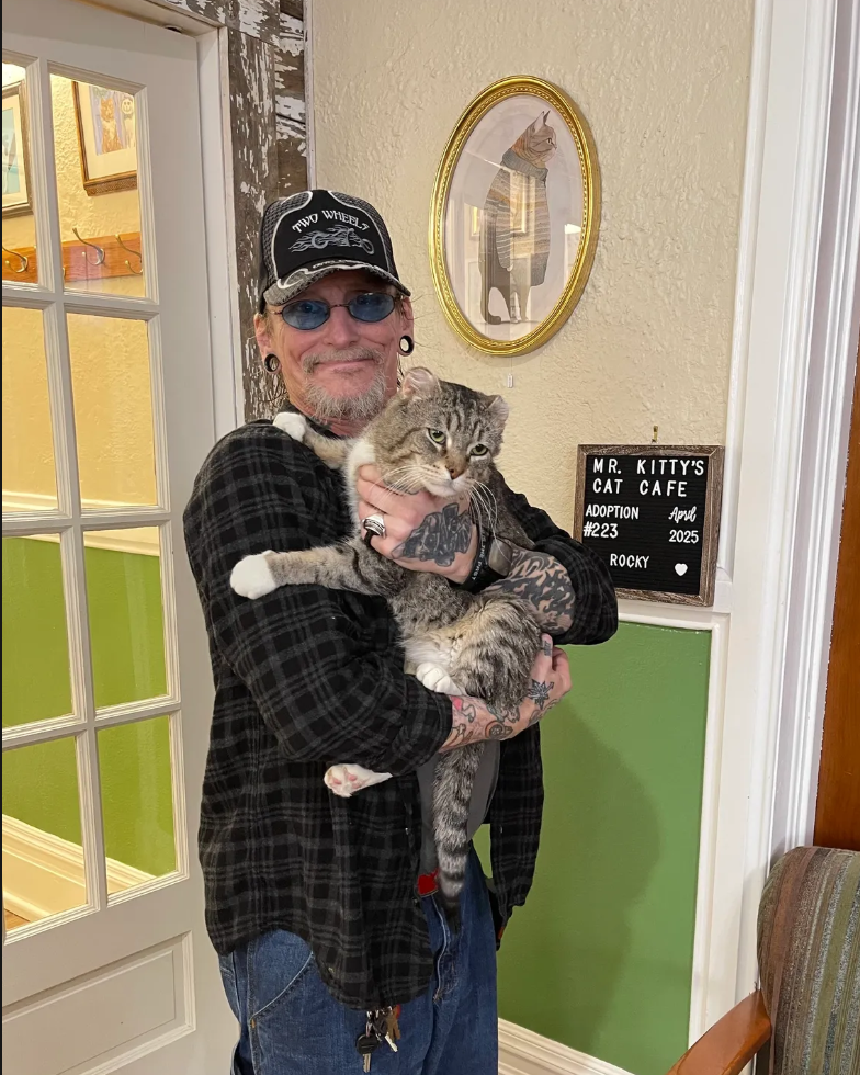 older man holding grey cat