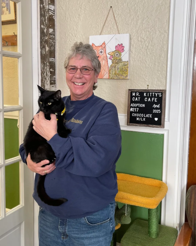 older person happily holding black cat