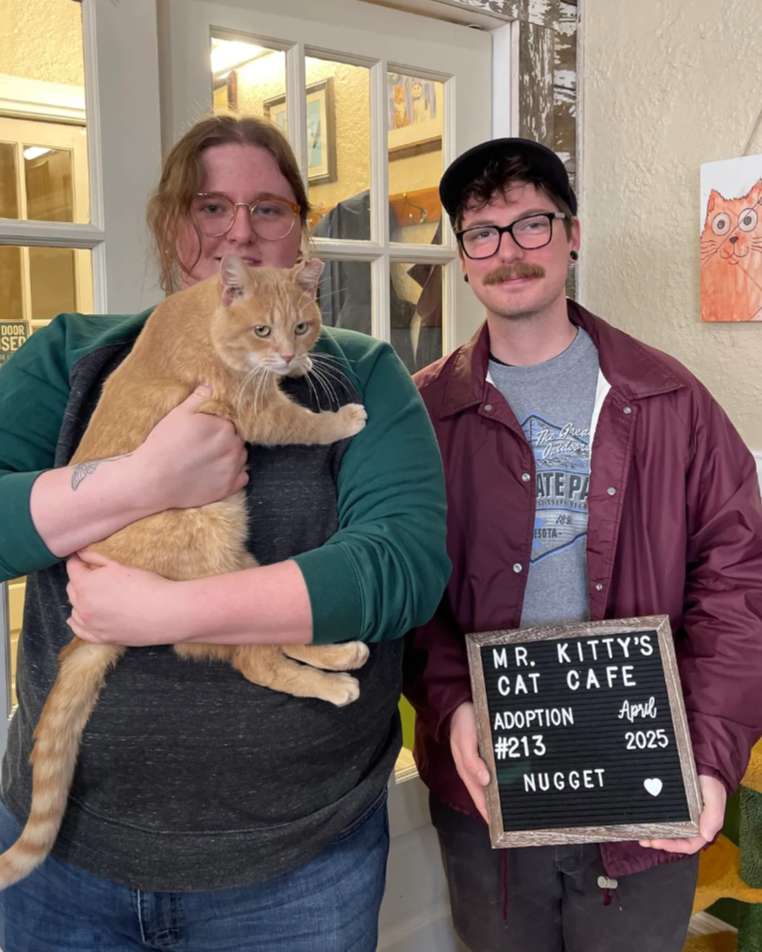 young couple holding an orange tabby cat